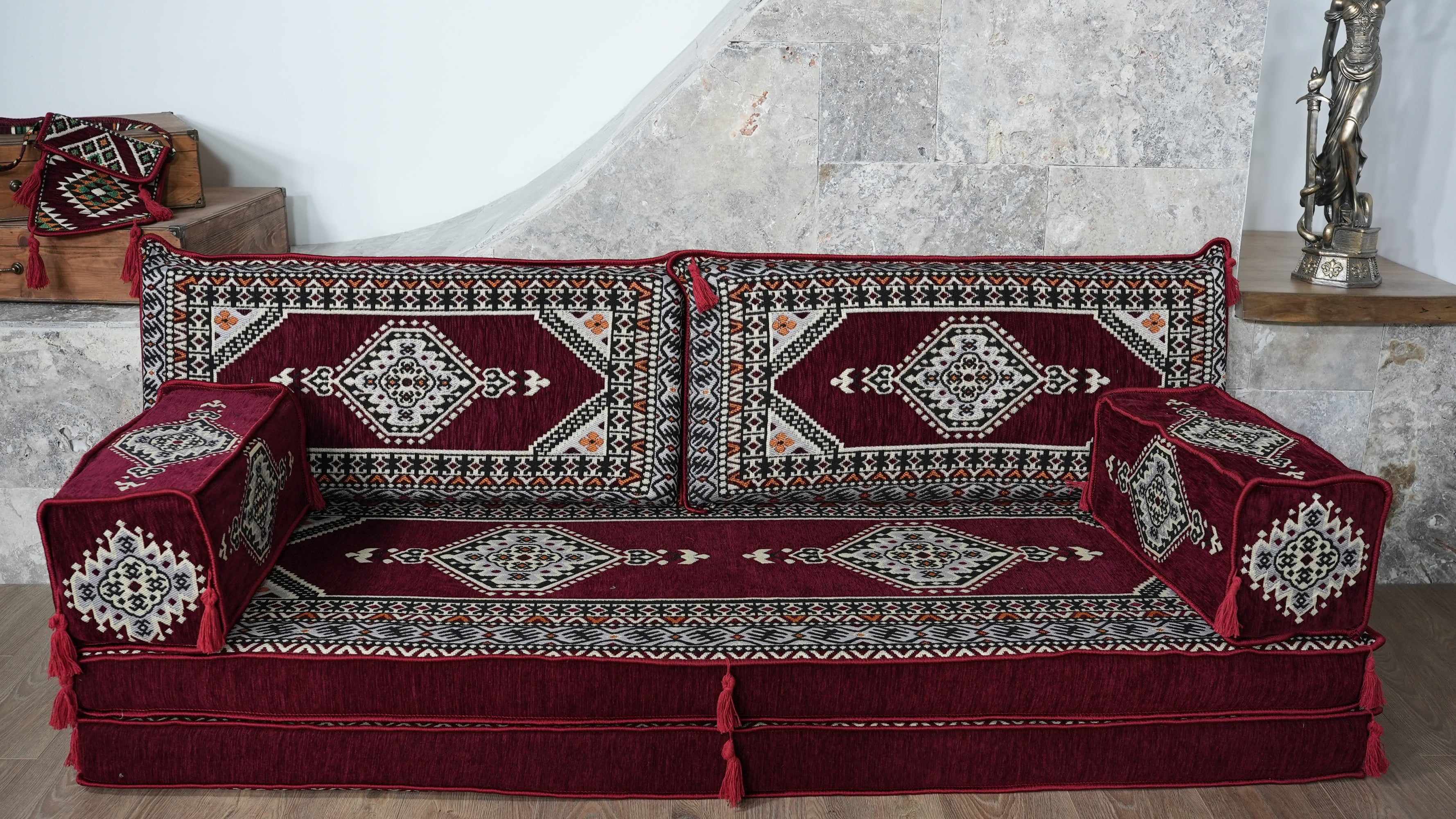 A low sofa covered with a matching deep red burgundy traditional patterned fabric set, shown indoors against a light stone wall in Chicago by Cozy Rugs.