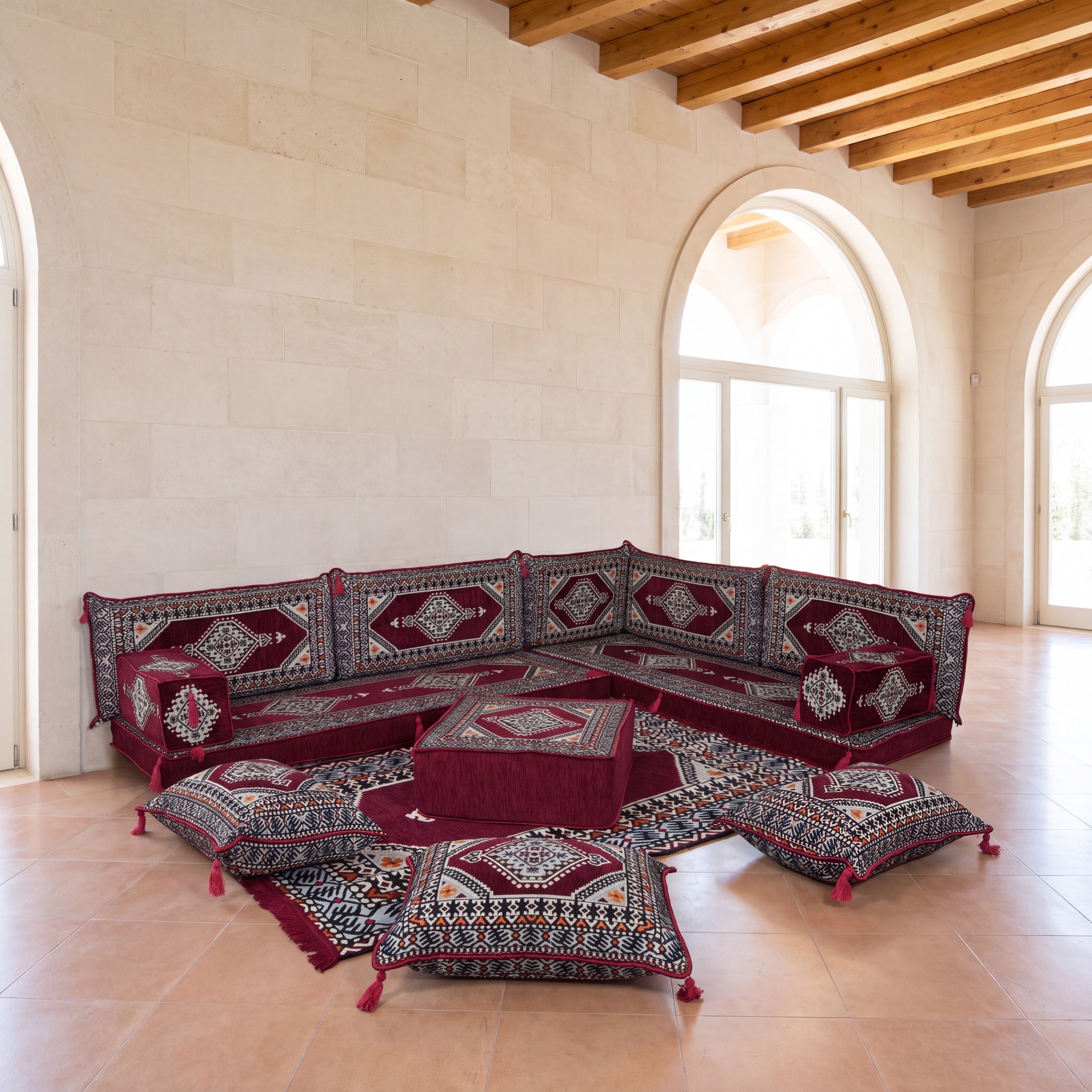 A modular set of traditional ARABIC MAJLIS floor cushions and a matching ottoman arranged in an L-shape in a spacious, sunlit room.