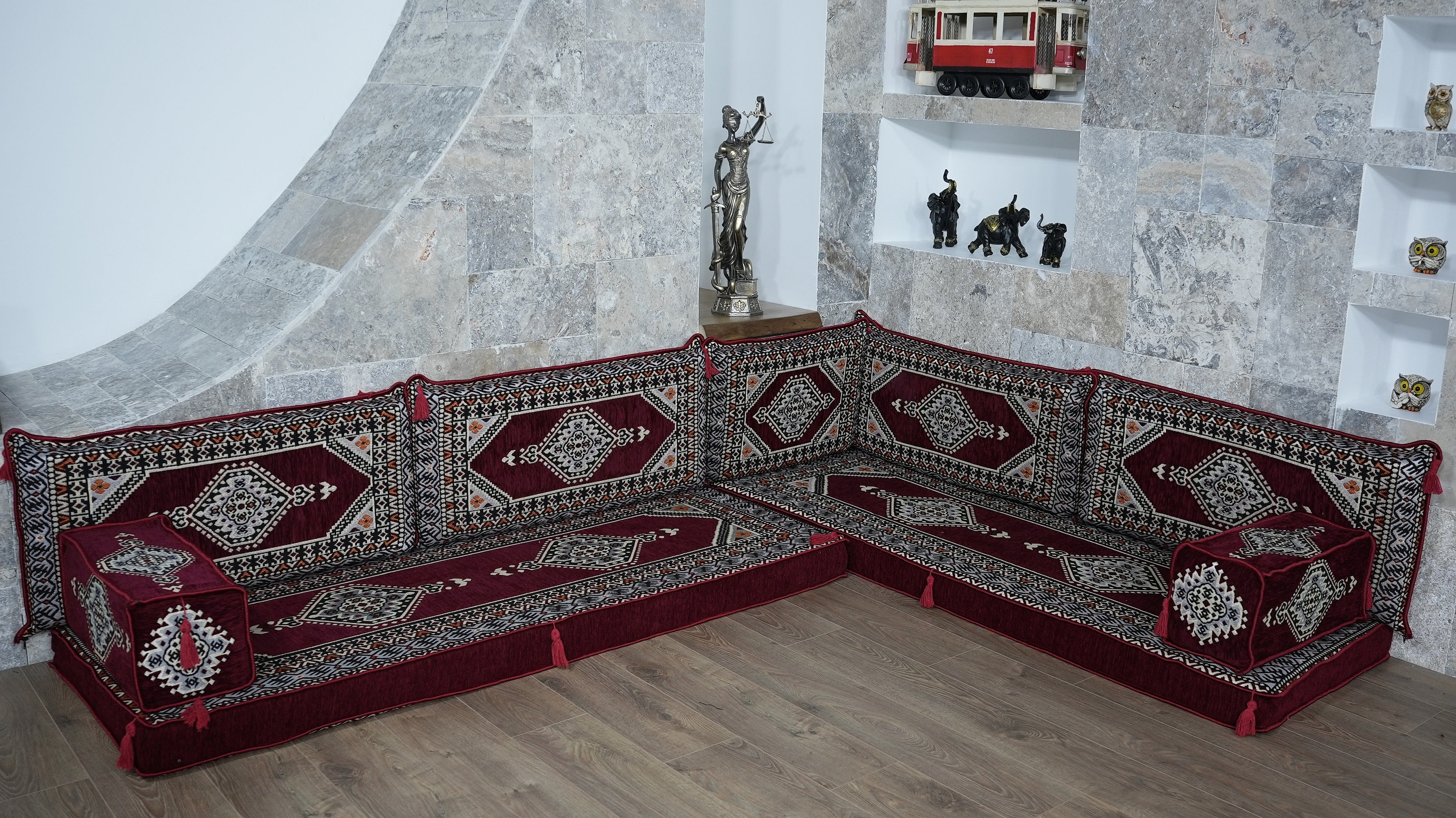 Decorative sectional Turkish Floor Seating sofa with intricate patterns in a room with stone walls and a mirror.