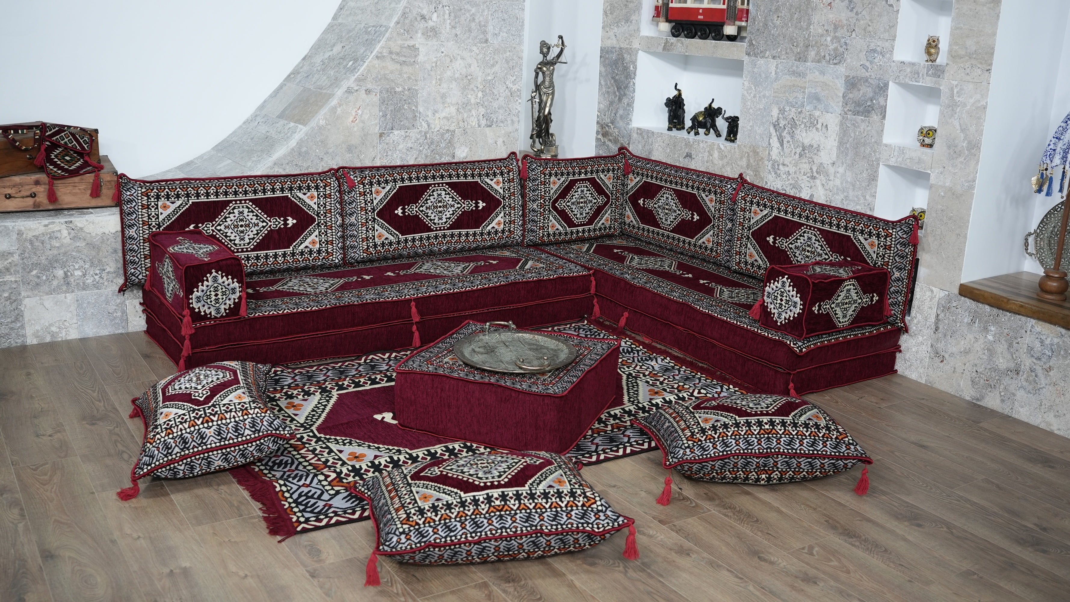 A traditional Turkish-style modular floor sofa set upholstered in deep red, burgundy with intricate geometric and arabic majlis patterns. The set includes multiple seat cushions, backrest cushions, and a central square ottoman on a matching patterned rug.