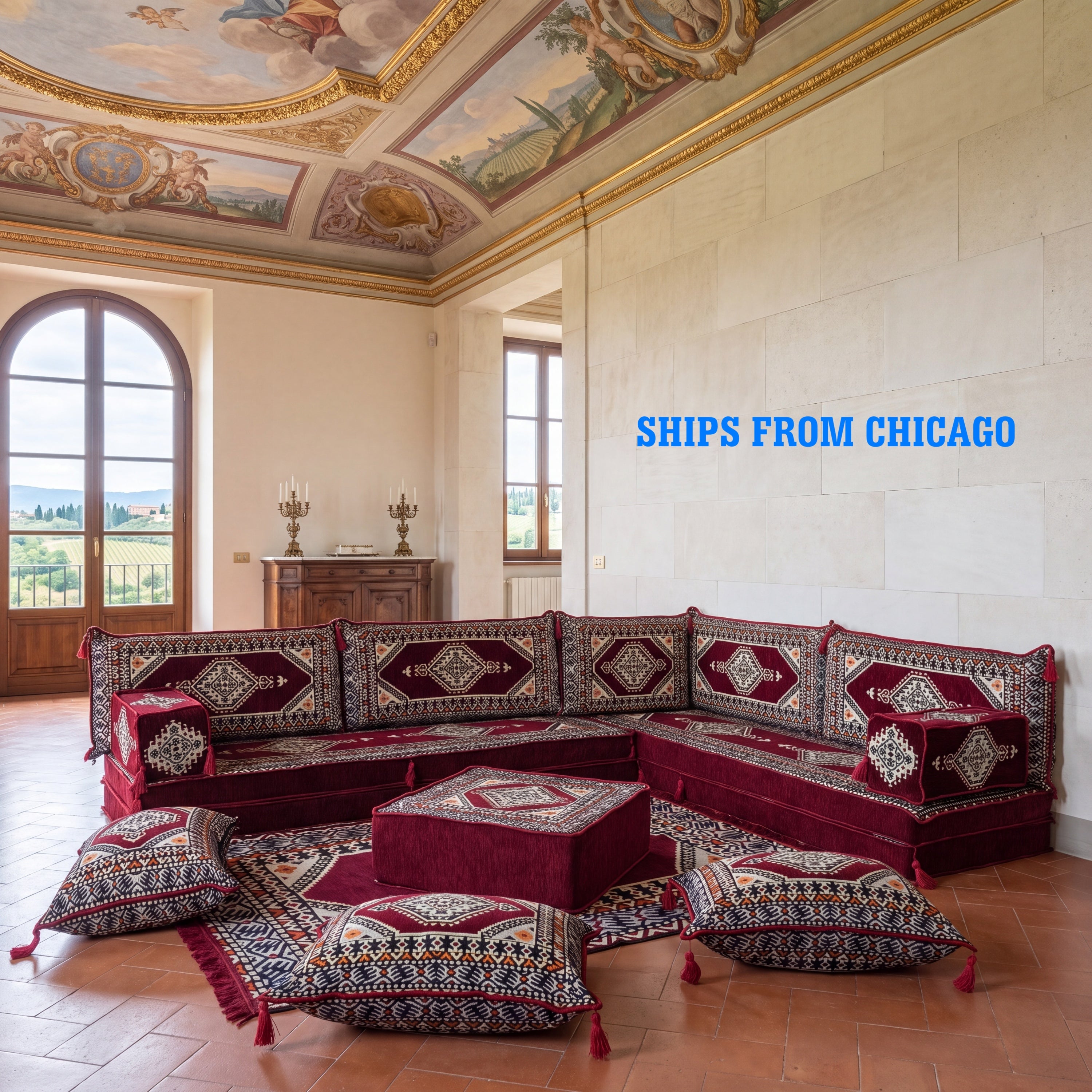A large traditional corner sectional sofa set with matching floor cushions in deep red BURGUNDY patterned fabric, arranged in a grand room with a painted dome ceiling and terracotta tile floor. Blue text on the right reads 'SHIPS FROM CHICAGO'