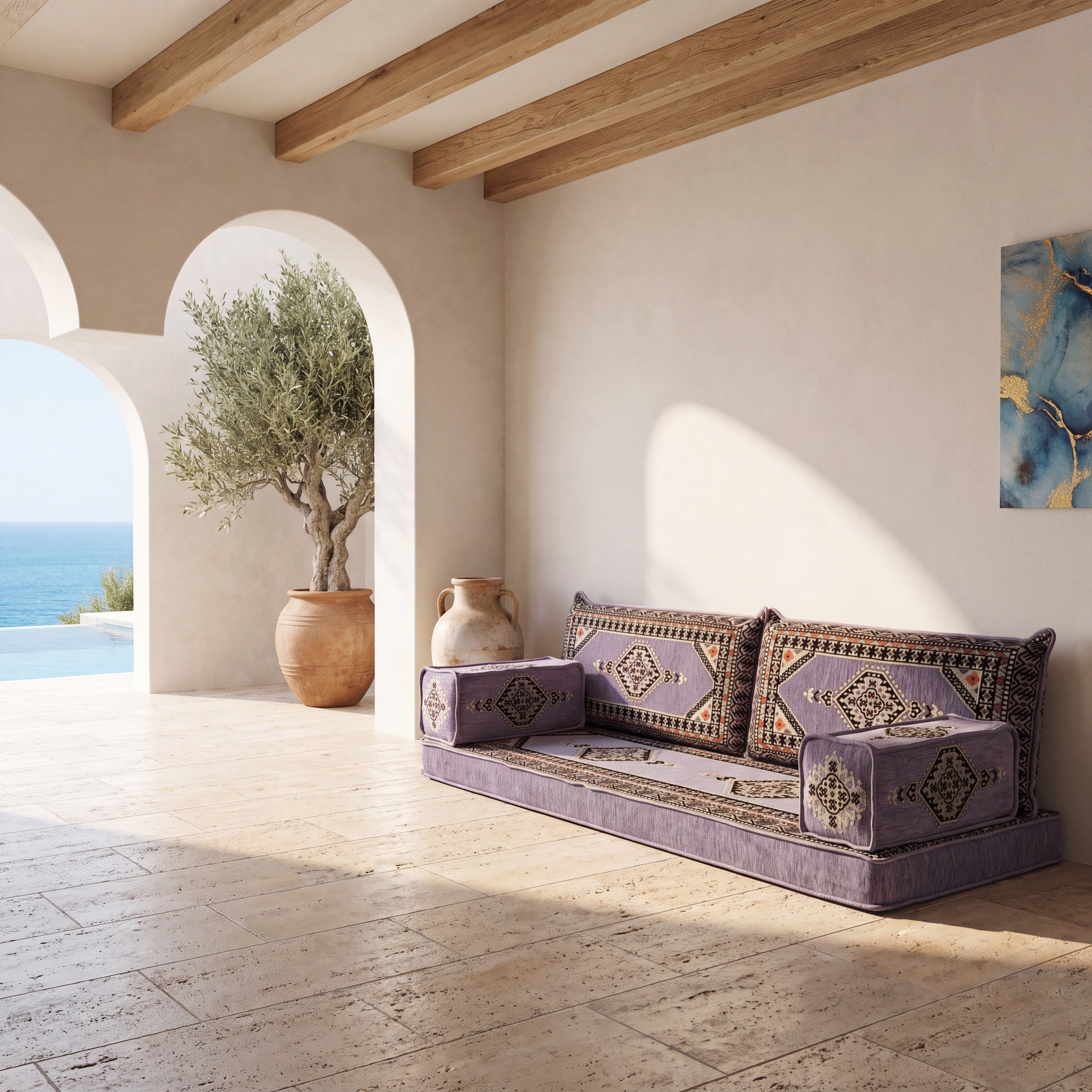 A gray Moroccan-style floor sofa with geometric patterned cushions, set in a sunlit Mediterranean patio with stone floors.