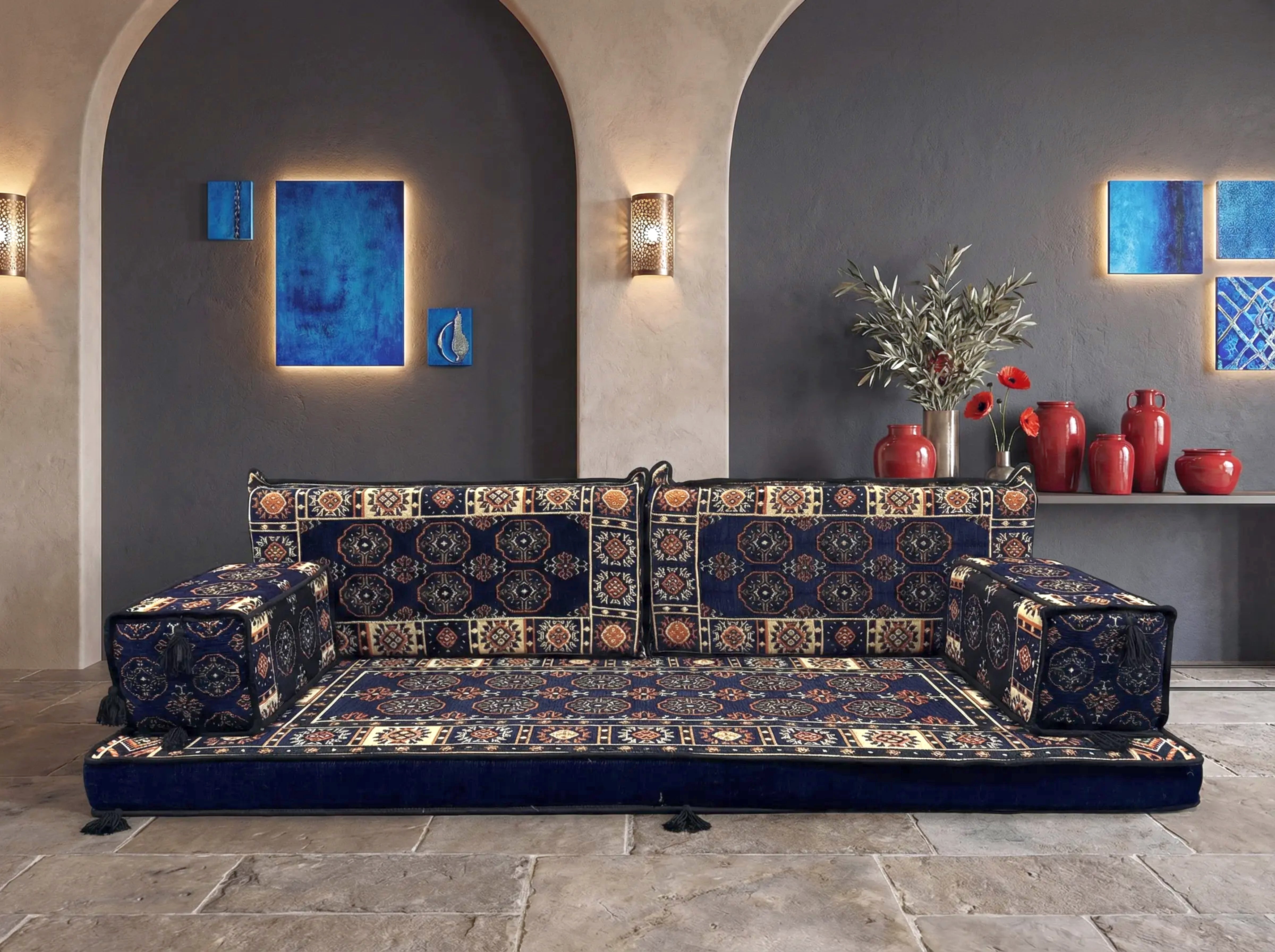 A low, traditional modular floor sofa with a dark navy blue base and bukhara patterned cushions styled in a modern Mediterranean interior.